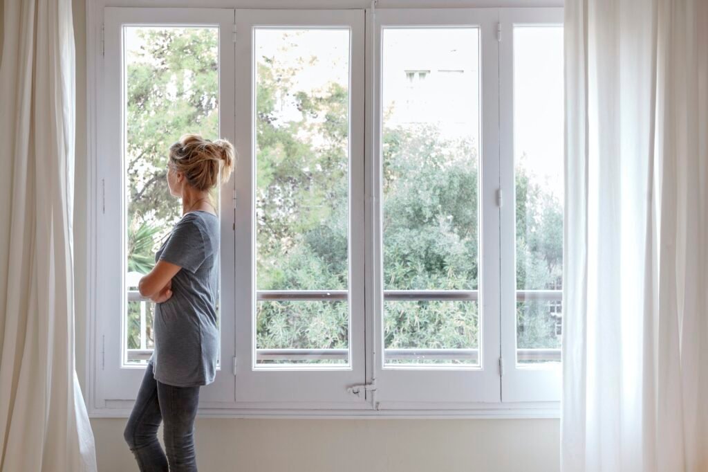 Woman at home, looking out of window